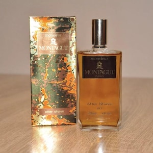 May include: A brown glass bottle of aftershave with a gold label that reads "Monsieur Montagut Paris" and "After Shave 60". The bottle is sitting on a wooden surface.