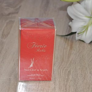 以下が含まれることがあります： 赤い箱に金色のデザインと「Feeerie Rubis」と「Van Cleef & Arpels」の文字が書かれています。箱は50mlの香水ボトル用です。