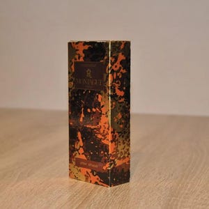 May include: A gold and brown box with a camouflage pattern. The box has the text "Montagut" and "after shave" on it.