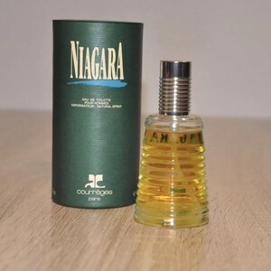 May include: A green and gold bottle of Niagara cologne by Courr&egrave;ges Paris. The bottle has a textured design and the label says "Eau de Toilette pour Hommes Vaporisateur Natural Spray".