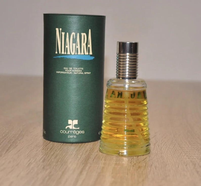 May include: A green and gold bottle of Niagara cologne by Courr&egrave;ges Paris. The bottle has a textured design and the label says "Eau de Toilette pour Hommes Vaporisateur Natural Spray".