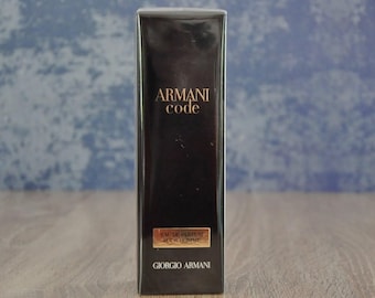 May include: A rectangular black box of Armani Code Eau de Parfum Pour Homme. The brand name and product name are in gold lettering. The bottom of the box reads "GIORGIO ARMANI".