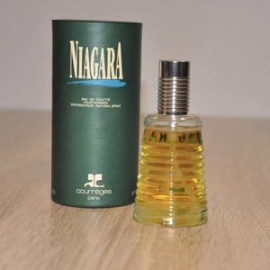 May include: A green and gold bottle of Niagara cologne by Courr&egrave;ges Paris. The bottle has a textured design and the label says "Eau de Toilette pour Hommes Vaporisateur Natural Spray".