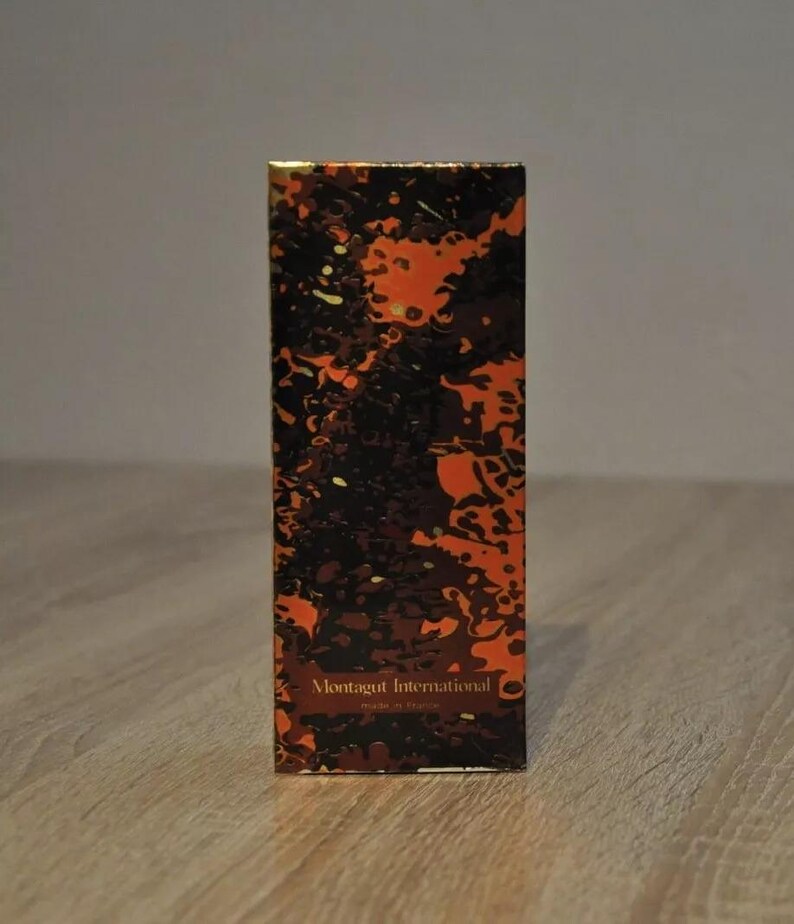 May include: A box with a black and orange abstract pattern. The text "Montagut International" is printed in gold on the front of the box.