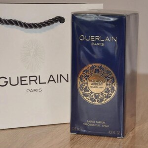 May include: A blue and gold perfume bottle with the text "Guerlain Paris" and "Patchouli Ardent Guerlain" on the front. The bottle is 4.2 fluid ounces and is packaged in a white box with the text "Guerlain Paris" on the front.