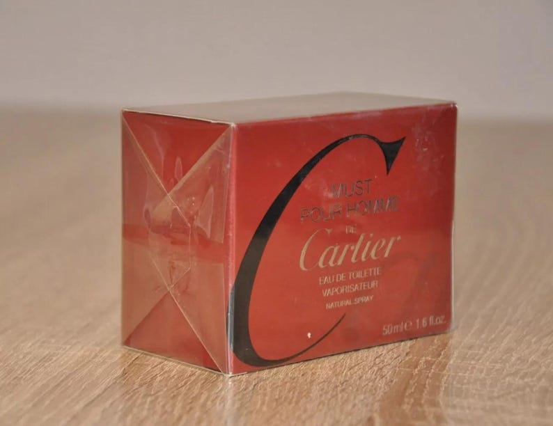 May include: A red Cartier Just For Her Eau de Toilette vaporisateur natural spray perfume box. The box features the Cartier logo and product details, including the volume (50ml e 1.6 fl.oz). The packaging is primarily red with black text and a gold-colored logo.