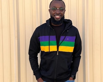 May include: A black zip-up hoodie with a purple, green, and yellow striped pattern. The hoodie has a hood and a zipper closure.