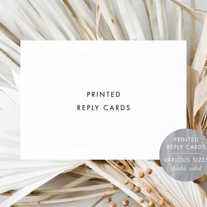 May include: White card with the text "PRINTED REPLY CARDS" on it. The card is sitting on a bed of dried beige and white palm leaves. A gray circle with the text "PRINTED REPLY CARDS VARIOUS SIZES double sided" is in the lower right corner of the image.