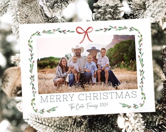 May include: A Christmas card with a family photo, framed by a green and red watercolour garland. The card reads "MERRY CHRISTMAS" and "The Carter Family 2024". The background is a snowy Christmas tree, with frosted branches.
