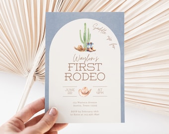 Könnte beinhalten: Eine hellblaue Einladungskarte mit weißem Hintergrund. Die Karte zeigt eine Aquarell-Illustration eines Kaktus, Cowboystiefeln und eines Cowboyhuts. Der Text auf der Karte lautet "Saddle up for Waylon's First Rodeo" mit Datum und Uhrzeit der Veranstaltung.