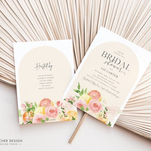 May include: A white card with a peach background and a floral design featuring lemons, oranges, and pink roses. The text on the card reads "You're invited to a Bridal Shower for Liz Carter" and includes the date, time, and location of the event.