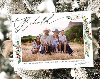 Può includere: Un biglietto di Natale con una foto di famiglia e la parola "Behold" in corsivo. Il biglietto è decorato con vegetazione e bacche ad acquerello. Il testo include "The Lamb of God..." e "Johnsen family 2023."