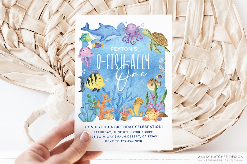 May include: A blue and white birthday invitation with an underwater theme. The invitation features a variety of sea creatures, including a dolphin, an octopus, a turtle, a jellyfish, and a seahorse. The text on the invitation reads "Peyton's O-Fish-Ally One" and includes details about the birthday celebration, including the date, time, and location.
