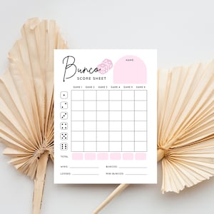 Op de afbeelding: Een printbaar Bunco-scoreblad met een roze dobbelsteenafbeelding. Het blad heeft ruimte om scores voor zes spellen, totale punten, winst, verlies, buncos en mini-buncos te registreren.