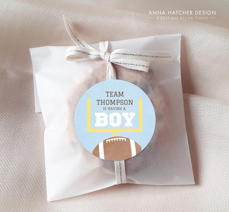 Może przedstawiać: Niebieska i biała etykieta na prezent z okazji baby shower z grafiką piłki nożnej i strefy końcowej. Etykieta zawiera napis "Team Thompson is having a Boy".