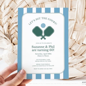 May include: A blue and white striped invitation card with the text "Let's Hit the Court!" and a graphic of two pickleball paddles. The invitation is for Suzanne and Phil's 60th birthday party, which will be held on Saturday, April 28th from 10am to noon at 123 Pickleball Lane, Indian Wells, CA 12345. Guests are asked to bring their paddle and RSVP to Anna at 123 456 7890.