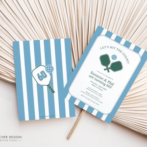May include: Blue and white striped invitation with the text "Let's Hit the Court!" and "Suzanne & Phil are turning 60!"  The invitation features a green and white illustration of two pickleball paddles and a ball.