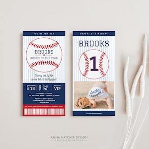 May include: Baseball-themed first birthday party invitation with a blue and red baseball graphic and the text "Brooks is Rookie of the Year". The invitation also includes a photo of a baby wearing a baseball cap and a onesie that says "Little Slugger".