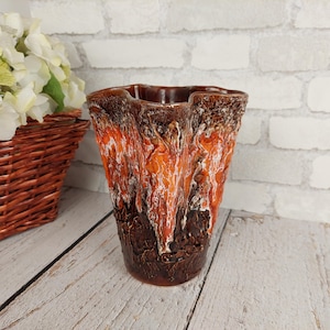 Peut inclure: Un vase en céramique brun et orange avec un design texturé et ondulé. Le vase a une large ouverture et une base étroite.