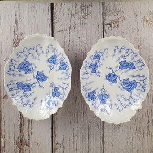 Peut inclure: Deux assiettes en céramique blanche avec des motifs floraux bleus. Les assiettes ont un bord festonné et un design en relief.