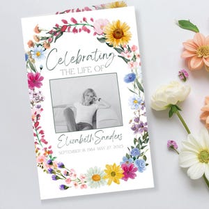 Peut inclure: Une carte de deuil avec un motif de couronne florale. La carte présente une photo en noir et blanc d'une femme, avec le texte "Célébrant la vie de Elizabeth Sanders" et les dates de naissance et de décès.