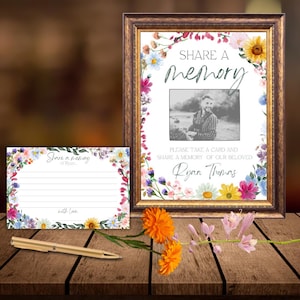 May include: A framed sign with the words "SHARE A memory" and a photo, surrounded by a floral border. A matching card and pen are next to the sign. The sign reads "PLEASE TAKE A CARD AND SHARE A MEMORY OF OUR BELOVED Ryan Thomas."