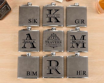 May include: Eight gray leather-wrapped hip flasks with silver accents. Each flask has a different personalized inscription, including initials, names, and a monogram.
