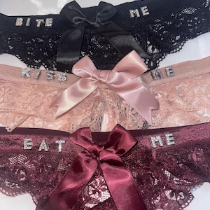 Tanga de encaje con lazo y dijes personalizados
