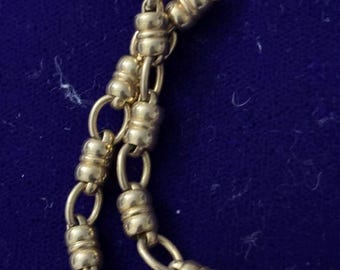 May include: A gold chain necklace with a unique design featuring alternating oval and round links. The chain is made of a smooth, polished metal.