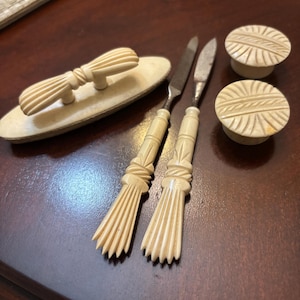 May include: A set of antique ivory manicure tools, including two files with carved handles, a small dish with a carved bow handle, and two round containers with carved lids.