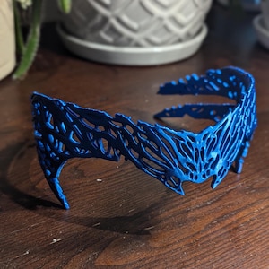 以下が含まれることがあります： 繊細で複雑なデザインの青いプラスチック製のヘッドバンド。ヘッドバンドは軽量素材で作られており、柔軟なデザインです。