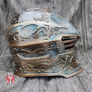 May include: A detailed, intricately carved helmet with a bronze and blue finish. The helmet has a visor with a series of horizontal bars. The helmet is decorated with a swirling, floral pattern.