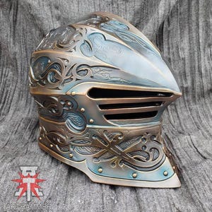 May include: A detailed, ornate helmet with a blue and gold finish. The helmet has a visor with a decorative grill and intricate engravings.