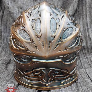 May include: A bronze helmet with intricate, ornate designs. The helmet has a rounded top and a pointed crown. The helmet is decorated with a pattern of swirling lines and shapes.