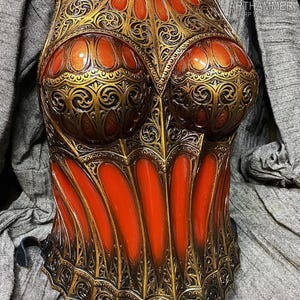 Op de afbeelding: Een sierlijk, goudkleurig borstpantser met ingewikkelde filigraan en rode accenten. Het pantser heeft een gebeeldhouwd ontwerp met een hoge halslijn en is vastgezet met zwarte bandjes. De afbeelding bevat de tekst "ARTHAMMER RPW WORKSHOP".