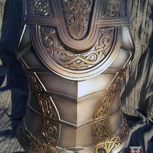 May include: A detailed, intricately carved, silver and gold breastplate with a Celtic knot design. The breastplate is made of metal and has a worn, aged look. It is a LARP costume piece.