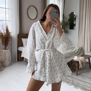 May include: A white floral print short-sleeved robe with a tie waist. The robe has a relaxed fit and a flowy silhouette.