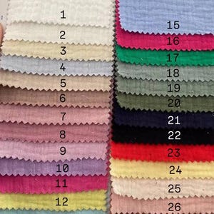 May include: A color swatch card featuring 28 fabric samples in various colors. The samples are arranged in rows and columns, showcasing a range of hues from white and beige to pink, blue, and green. Each swatch is labeled with a number.
