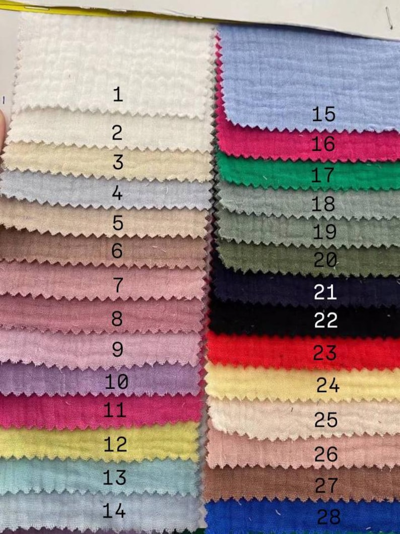 May include: A color swatch card featuring 28 fabric samples in various colors. The samples are arranged in rows and columns, showcasing a range of hues from white and beige to pink, blue, and green. Each swatch is labeled with a number.
