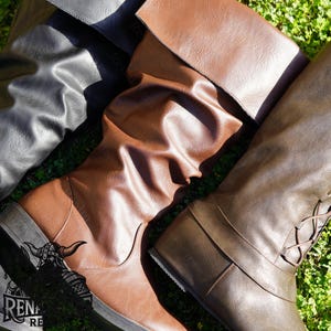 May include: Three pairs of knee-high boots in brown, black, and dark brown leather. The boots have a pointed toe and a low heel.