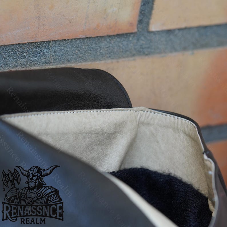 May include: Close-up of the inside of a black leather boot. The boot is lined with a soft, beige fabric and has a black fleece lining. The boot has a black leather sole and a black leather heel.