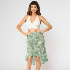 May include: A woman wearing a white halter top and a green floral print high-low skirt with a ruffle hem.