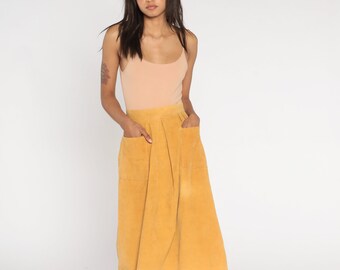May include: A mustard yellow corduroy skirt with two front pockets. The skirt is knee-length and has a fitted waist.