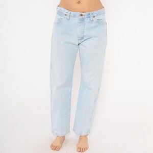 May include: Light blue denim jeans with a classic five-pocket design. The jeans have a straight leg fit and a button and zipper closure. The light wash denim has a faded appearance, giving them a vintage look. A casual, everyday wardrobe staple.