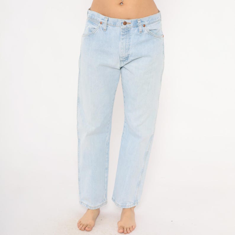 May include: Light blue denim jeans with a classic five-pocket design. The jeans have a straight leg fit and a button and zipper closure. The light wash denim has a faded appearance, giving them a vintage look. A casual, everyday wardrobe staple.