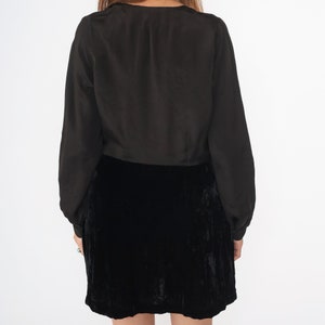 May include: A black velvet mini skirt with a black long-sleeved blouse.