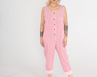 May include: A pink and white striped jumpsuit with a button-up front and cuffed legs. The model is wearing white sneakers.