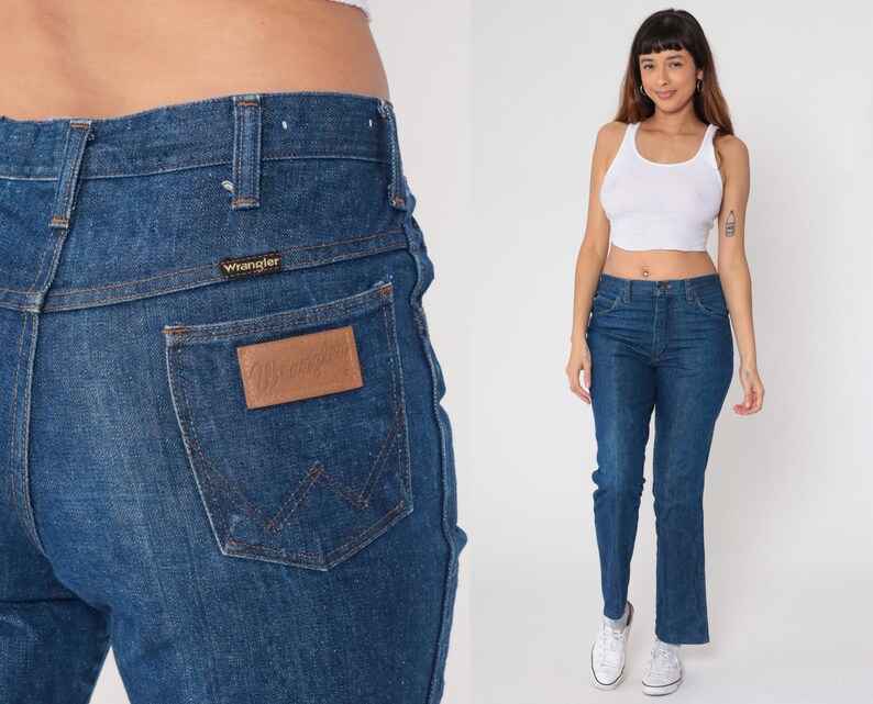 May include: Dark blue denim Wrangler jeans. The jeans have a classic five-pocket design, a straight leg, and a brown leather patch on the back pocket. The Wrangler logo is visible on the patch and above the back pocket.