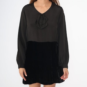May include: A black long-sleeved dress with a velvet skirt and a ruffled bow detail at the neckline.