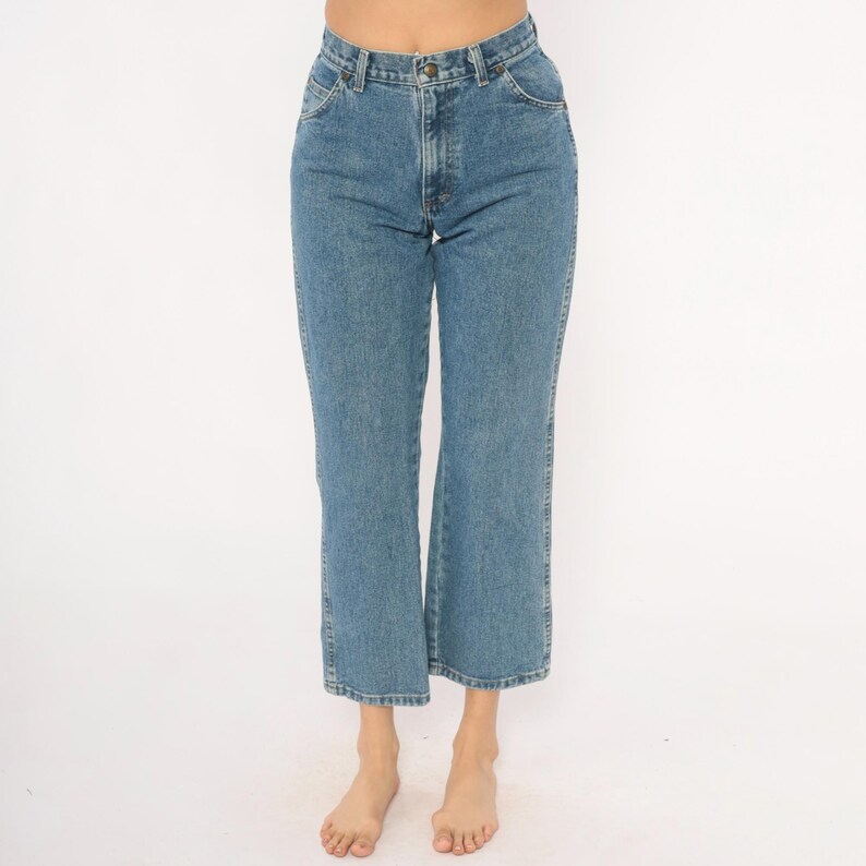 May include: Light blue denim jeans with a classic five-pocket design. The jeans have a straight leg cut that flares slightly at the ankle. The jeans are made of a durable denim material and feature a button and zipper closure.